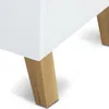 A close-up view of the bottom corner of a white cabinet with wooden legs. Náhled obrázku produktu