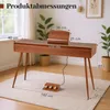 A digital piano with dimensions indicated by text overlays, placed on a rug in a room with plants and a window. Produktbild-Vorschau