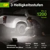 A person is changing a tire on a truck at night, illuminated by a portable work light. Anteprima dell’immagine prodotto