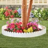 A white plastic garden border around a tree trunk with colorful flowers. Produktbild-Vorschau