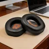 Two black ear pads are placed on a tan desk mat, with a laptop and a computer monitor in the background. Voir les images du produit