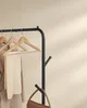 A clothing rack with clothes and a handbag on a neutral background. Náhled obrázku produktu