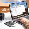 A person is using a laptop connected to an external CD/DVD drive, with a camera in the background. Produktbild-Vorschau