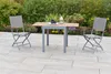 A garden table and two chairs set up on a patio with plants in the background. Produktbild-Vorschau
