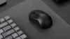 A black wireless mouse and a portion of a keyboard are placed on a dark gray mousepad. Produktbild-Vorschau