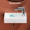A close-up view of a white ceramic washbasin with a chrome faucet, set against an orange wall. Text indicates a measurement. Voir les images du produit
