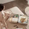 A woman is packing a suitcase with a hairdryer and other travel items. Anteprima dell’immagine prodotto