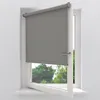 A gray roller blind is installed on a white window frame. The window is open, revealing trees and greenery outside. Produktbild-Vorschau