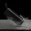 A black Sony Bluetooth speaker is shown at an angle, with dust or debris exploding around it, against a black background. Voir les images du produit