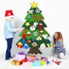 Two children are decorating a felt Christmas tree with various ornaments and gifts are placed around the base of the tree. Voir les images du produit