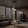 A modern living room with a sectional sofa, coffee table, bookshelf, and a large window overlooking a city at night. A pendant light fixture hangs from the ceiling. Náhled obrázku produktu