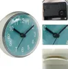 A collage of images showing a mini wall clock with a suction cup, a close-up of the clock mechanism, and a close-up of the clock hands. Produktbild-Vorschau