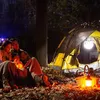 A family camping at night, sitting around a campfire with a tent in the background. Anteprima dell’immagine prodotto