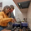A couple cooking together in a kitchen, with a range hood visible above the stovetop. Anteprima dell’immagine prodotto