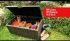 A brown storage box with its lid open, filled with garden tools, sitting on a lawn with greenery in the background. Podgląd zdjęcia produktu