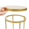 A hand is holding a round gold tabletop above a gold stand, showing how they connect. Podgląd zdjęcia produktu