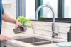 A person is pouring liquid from a vacuum cleaner dustbin into a kitchen sink. Voir les images du produit