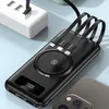 A black wireless power bank with integrated cables is shown connected to a white power strip, with a smartphone partially visible in the foreground. Produktbild-Vorschau