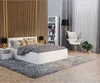 A modern bedroom with a white bed, wooden wall paneling, a bookshelf, and an armchair. Produktbild-Vorschau