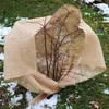 A burlap fabric wrapped around a small tree in a garden with patches of snow. Náhled obrázku produktu