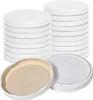 Stacks of white screw-on lids for jars, with one lid shown open to reveal its tan interior. Produktbild-Vorschau