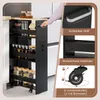 A person's hand is shown pulling a narrow kitchen cart out from a gap between cabinets. The cart is filled with jars of spices and other kitchen items. Inset images highlight the cart's handle, railings, and wheels. Podgląd zdjęcia produktu