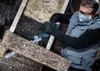 A person is using a reciprocating saw to cut insulation material in an attic or similar construction environment. Voir les images du produit