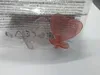 Two pacifiers in heart shapes are shown inside a clear plastic package. Produktbild-Vorschau