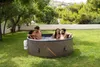 Four people relaxing in a hot tub in a grassy backyard. Náhled obrázku produktu