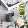 A ceramic storage jar filled with brown sugar crystals sits next to a glass of iced tea and a book. Produktbild-Vorschau