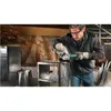 A man is using an angle grinder to cut metal in a workshop. Podgląd zdjęcia produktu