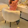 A person sits at a vanity table, with a fluffy white chair in the foreground. Produktbild-Vorschau