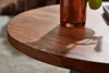 Close-up of a round wooden table with a copper vase on it, casting a shadow. Náhľad obrázku produktu