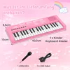 A pink toy keyboard with dimensions and included accessories shown against a pink background with musical notes and a rainbow illustration. Produktbild-Vorschau