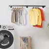 A laundry room scene with a washing machine, a clothes rack with hanging clothes, and a laundry basket. Produktbild-Vorschau