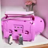 The back of a pink boombox with two penguin figurines in front of it, placed on a shelf with some crocheted flowers in the background. Produktbild-Vorschau