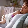 A father is holding his baby, who is sleeping with a pacifier. Produktbild-Vorschau