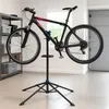 A bicycle is mounted on a repair stand in a garage or workshop. Podgląd zdjęcia produktu