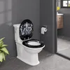 A white toilet with a black toilet seat featuring a decorative design is shown in a modern bathroom setting. Produktbild-Vorschau