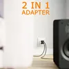 A close-up shot of a white wall with an electrical outlet and a black 2-in-1 adapter plugged in. A black speaker is visible on the right side of the image. Produktbild-Vorschau