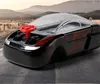 Schwarzes Spielzeugauto mit durchsichtigem Dach und rotem Lenkrad, geparkt auf Asphalt mit Bergen im Hintergrund Produktbild-Vorschau