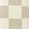 A close-up, top-down view of a carpet with a checkered pattern of cream and beige squares. Podgląd zdjęcia produktu