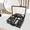 A black makeup case filled with various makeup products, open on a light-colored surface with a blurred background of a vanity and mirror. Produktbild-Vorschau