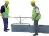 Two construction workers are using a lifting device to place a concrete block. Anteprima dell’immagine prodotto