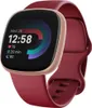A Fitbit Versa 4 fitness tracker with a raspberry red band and copper rose casing, displayed against a white background. Podgląd zdjęcia produktu