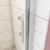 A close-up view of a shower door handle and the tiled wall behind it. Produktbild-Vorschau