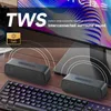 Two portable Bluetooth speakers are placed on a wooden surface in front of a large screen, with a keyboard in the foreground. The speakers are connected wirelessly, indicated by curved lines emanating from them. Produktbild-Vorschau