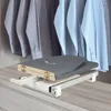 A folded ironing board is shown extended from a closet shelf, with shirts hanging in the background. Podgląd zdjęcia produktu