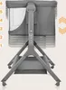 A close-up view of a gray baby crib with adjustable height settings. Produktbild-Vorschau