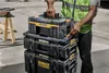 A person in a high-visibility vest is stacking toolboxes. Anteprima dell’immagine prodotto